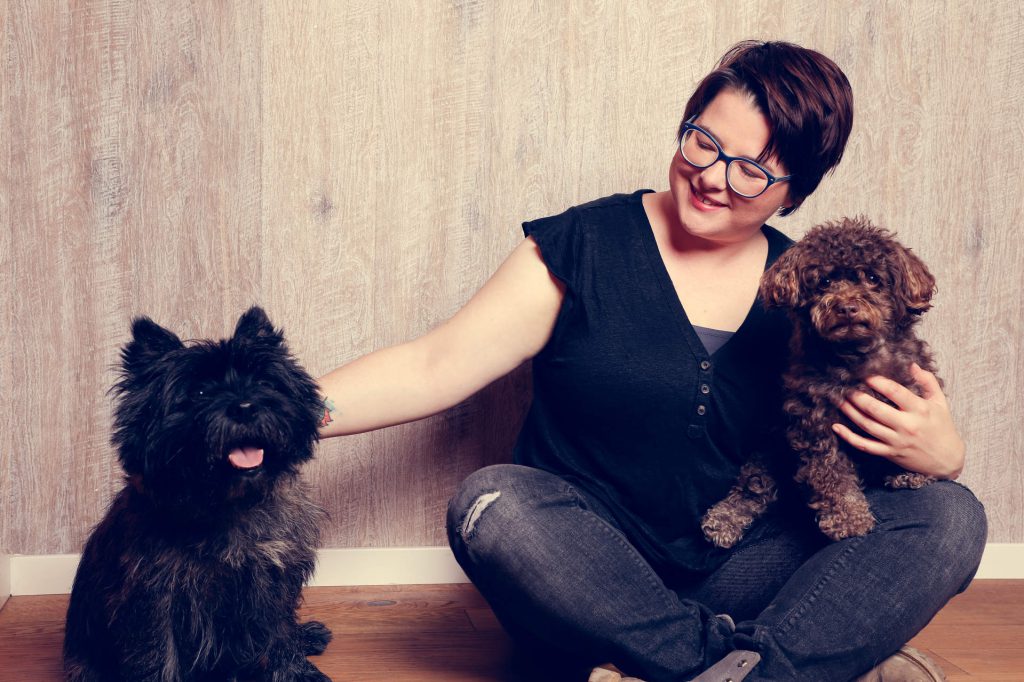 Annika sitzt mit zwei Hunden auf dem Boden.